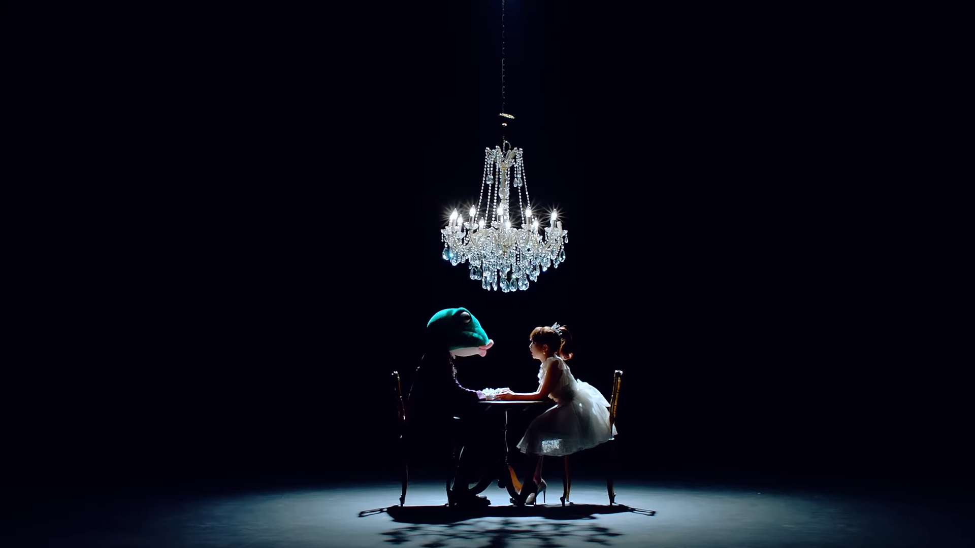 The frog and Yeojin sitting at a table under a chandelier.